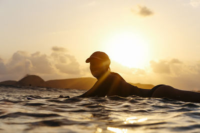 Female surfer lying on surfboard in the evening