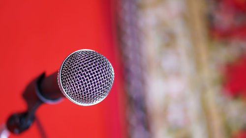 Close up of microphone in concert hall room on red background concept.