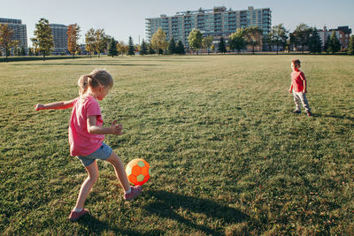 Children playing with ball on grassy land in park