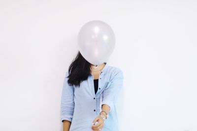 Midsection of woman holding balloons against white background