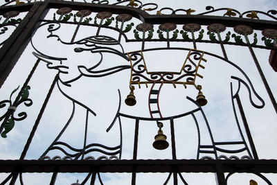 Low angle view of metal gate against sky