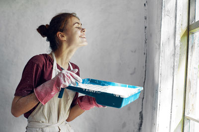 Side view of young woman standing against wall