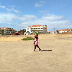 Full length of woman walking on street by buildings against sky