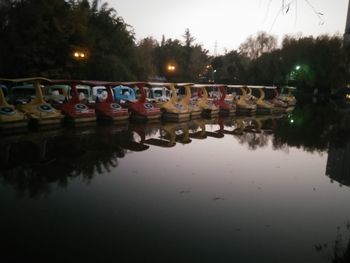 Reflection of illuminated trees on water against sky