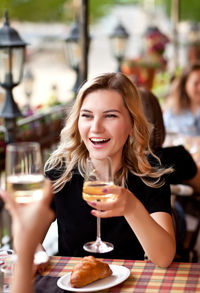 Portrait of a smiling young woman with drink in restaurant