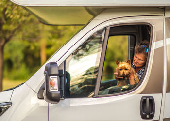 Senior woman with dog sitting in truck