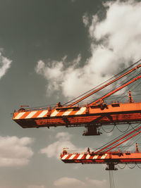 Low angle view of crane at construction site against sky