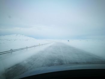 Scenic view of snow covered landscape seen through car windshield