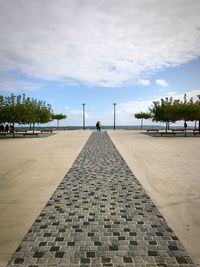 Distant view of people by sea against cloudy sky