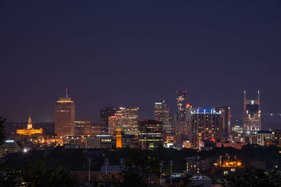 Illuminated buildings in city against sky at night