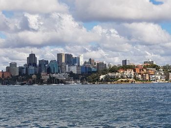 Sea by cityscape against sky