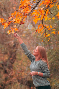 Woman standing by tree during autumn