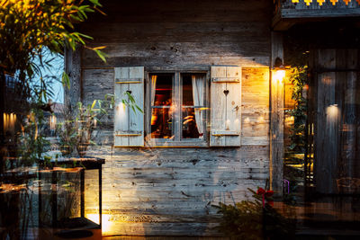 Old wooden house with christmas decoration and reflection on window