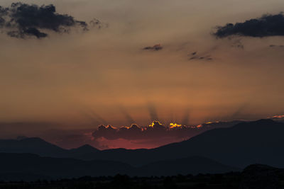 Scenic view of silhouette mountains against romantic sky at sunset