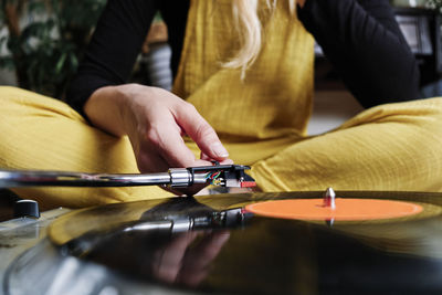 Woman adjusting tonearm of turntable at home