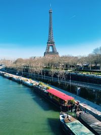 Paris cityscape along the seine river with trees and boats and the eiffel tower on a sunny day