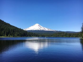 Scenic view of lake and mountains against clear blue sky