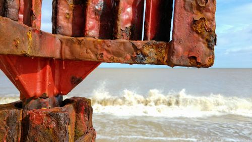 Close-up of rusty metal by sea against sky