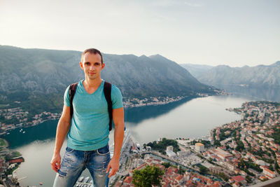 Portrait of mid adult man standing against river in city