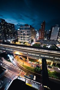 High angle view of illuminated street amidst buildings against sky