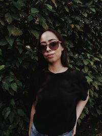 Portrait of smiling young woman standing against plants