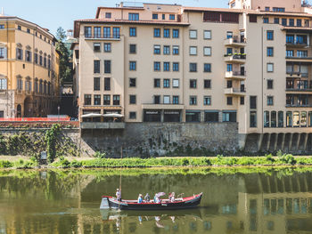 Boats in lake against buildings in city