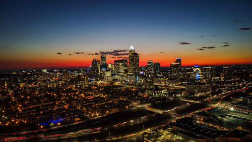 Aerial view of illuminated cityscape against sky during sunset