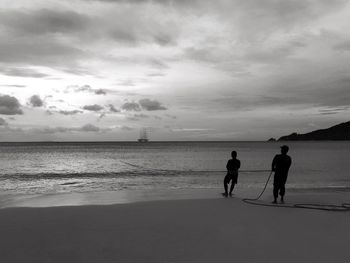 Silhouette men on beach against sky