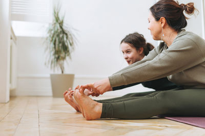 Attractive mother middle age woman and daughter teenager ptactice yoga together in the bright room