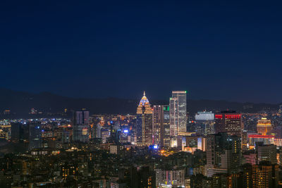 Illuminated modern buildings against clear sky at night