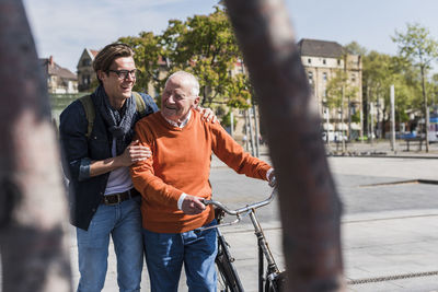 Happy senior man with adult grandson in the city on the move