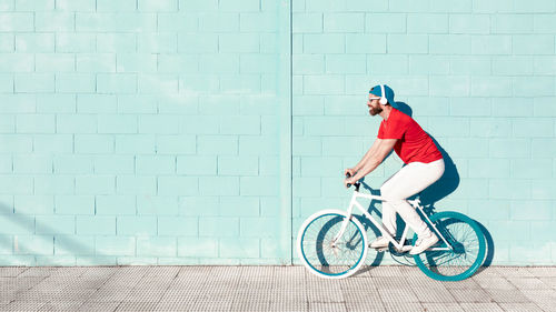 Side view of man riding bicycle against wall