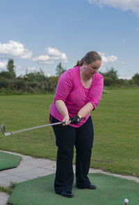 Full length of woman playing golf on field