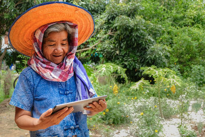 Senior woman holding digital tablet while standing at farm