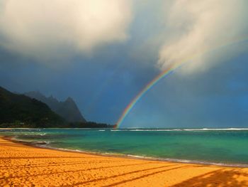Scenic view of sea against rainbow in sky
