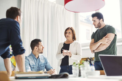 Mature businesswoman with male colleagues discussing project in office