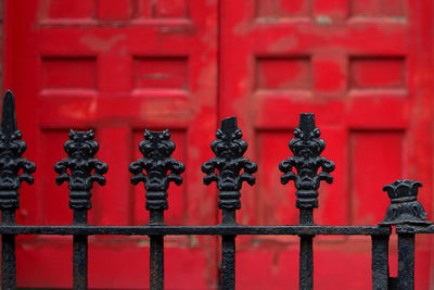 Close-up of metal fence against red building