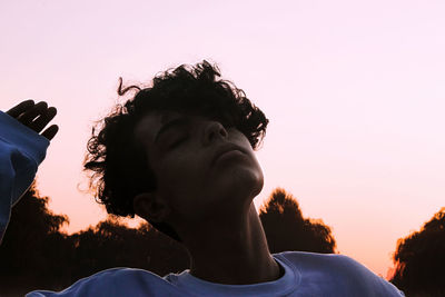 Low angle portrait of man looking at sunset against sky