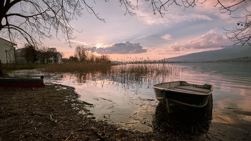 Boat moored in lake against sky during sunset