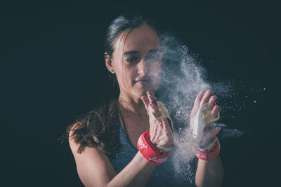 Portrait of woman holding hands against black background