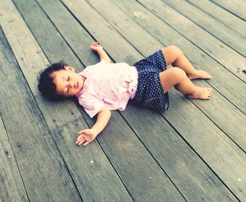 High angle view of baby lying on wooden floor