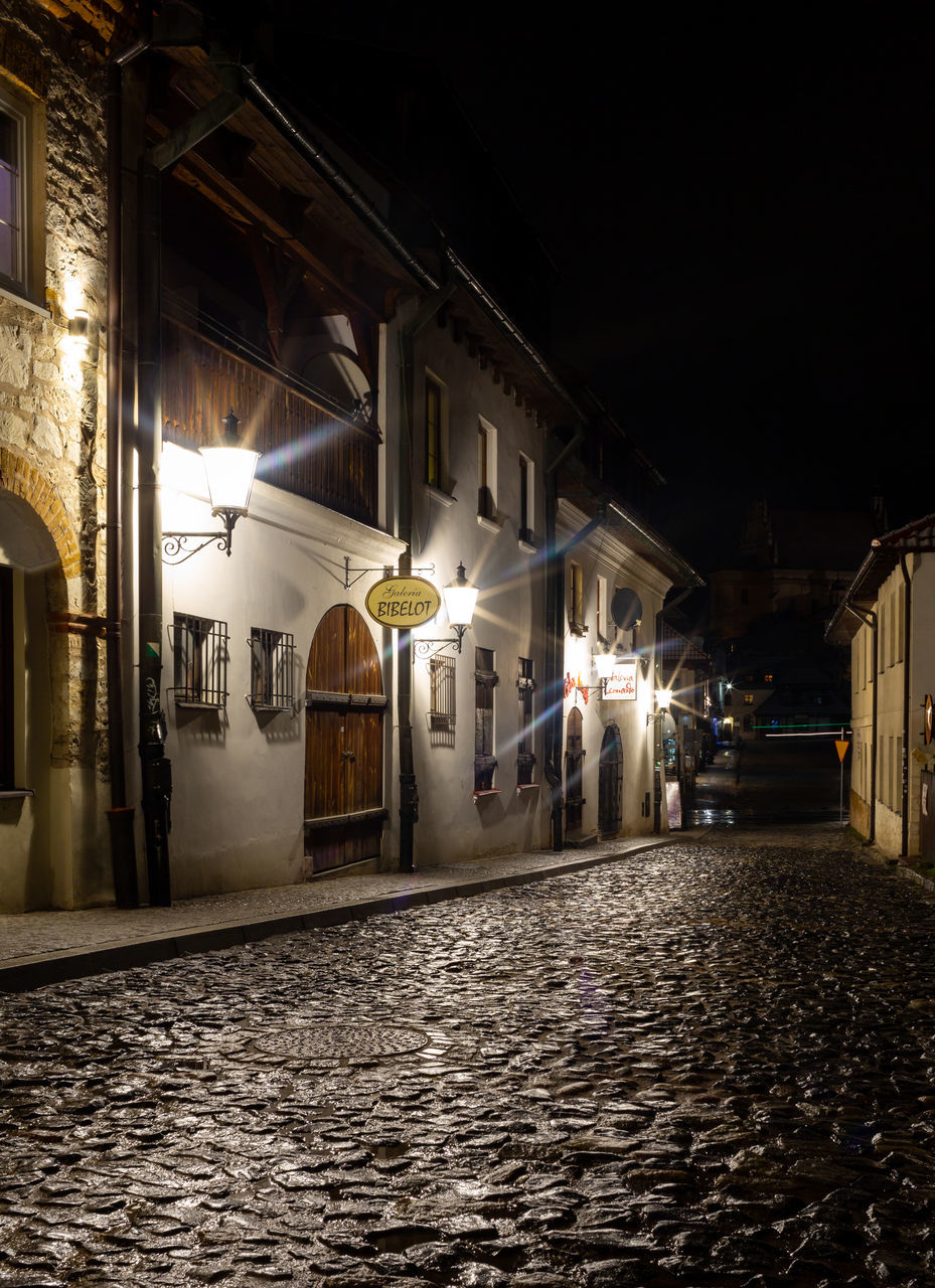 night, architecture, light, darkness, built structure, street, building exterior, lighting, city, urban area, evening, illuminated, cobblestone, road, building, no people, alley, transportation, lighting equipment, outdoors, residential district