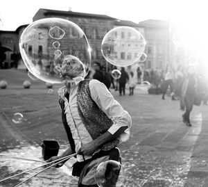 Man blowing bubbles on street in city