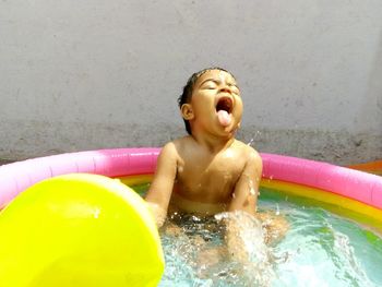 Shirtless boy swimming in wading pool