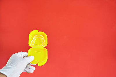 Close-up of hand holding yellow against red background