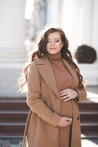 Smiling pregnant woman standing on street