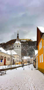 Snow covered buildings in city against sky