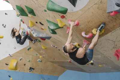 Man and woman bouldering in climbing gym