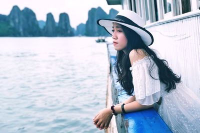 Young woman looking away while standing in boat on sea