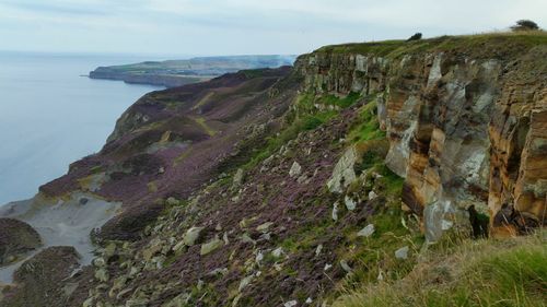 Scenic view of cliff by sea against sky